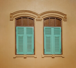Vintage window with blue shutters on yellow wall background. Retro style.