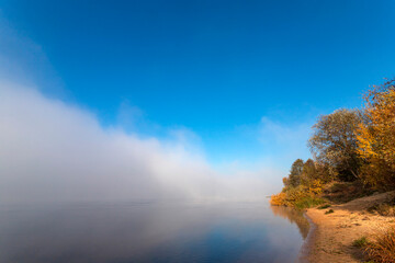 Thick fog on the river. Idyllic autumn landscape