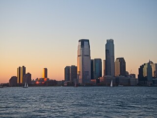 Fototapeta na wymiar The high rises of Jersey City tower over the Hudson River at dusk