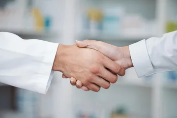 Zelfklevend Fotobehang Doctor, handshake and partnership in support at pharmacy for healthcare success, promotion or deal at clinic. Medical expert shaking hands in teamwork for life insurance, b2b or pharmaceutical needs © Anela/peopleimages.com