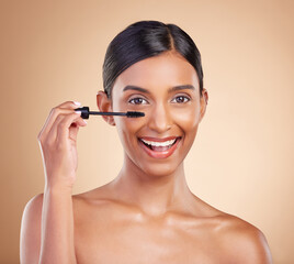 Portrait, beauty and mascara with a model woman in studio on a beige background to promote makeup. Face, eye and product with an attractive young female posing for cosmetics or luxury wellness