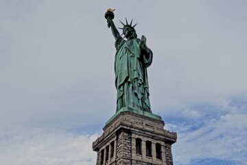 Fototapeta na wymiar The Statue of Liberty sits on Liberty Island in the New York Harbor. It was once a beacon of hope for immigrants arriving by steamship into the United States