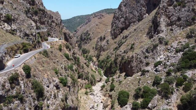 Dry River Between Steep Walls Of Narrow Canyon At Topolia Gorge In Crete, Greece. aerial tilt-down