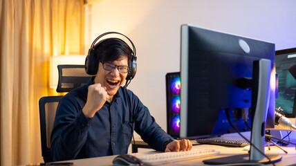 Happy Professional Asian male gamer playing video games on personal pc computer. Esport online game.