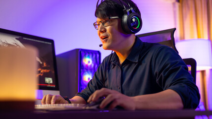 Professional Asian male gamer playing video games on personal pc computer. Colorful neon light room. Esport online game. © NVB Stocker