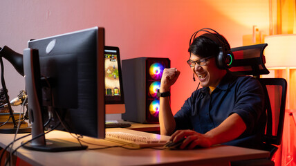 Professional Asian male gamer playing video games on personal pc computer. Colorful neon light room. Esport online game. © NVB Stocker