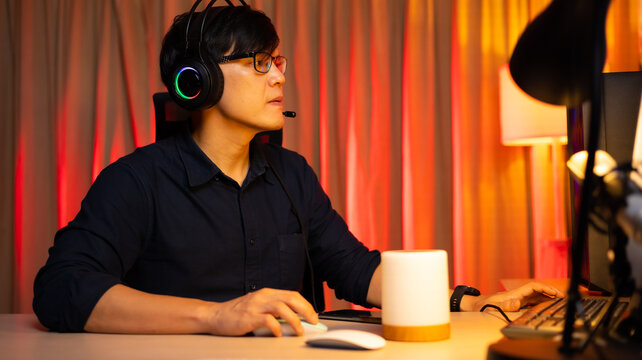 Professional Asian male gamer playing video games on personal pc computer. Colorful neon light room. Esport online game.