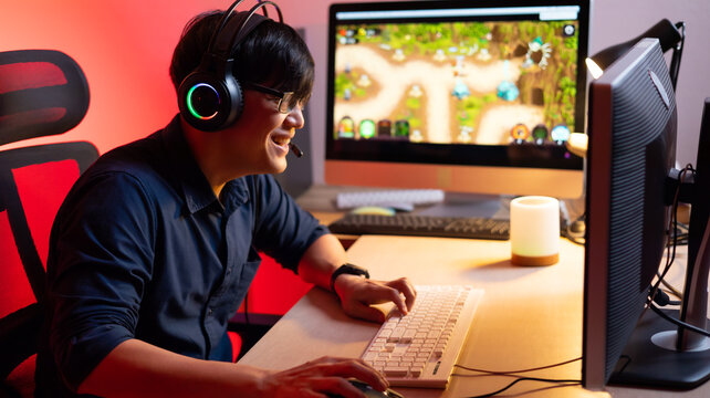 Professional Asian male gamer playing video games on personal pc computer. Colorful neon light room. Esport online game.
