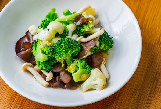Healthy food menu, stir-fried mushrooms, cauliflower, and broccoli, Thai healthy mix vegetable food on a white plate. Close-up image, view from above.
