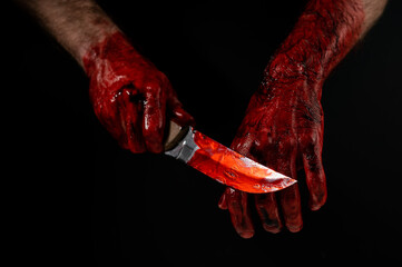 Man holding knife with bloody hand on black background. 