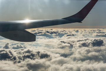 Wing of a flying plane above endless clouds
