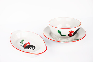 A set of white plates with a rooster design on it.  isolated with white background