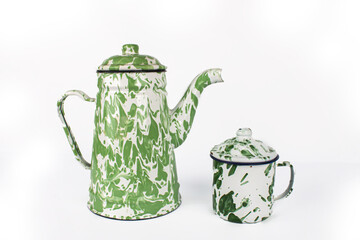 A vintage green white teapot and a small green cup are next to it. isolated on white background