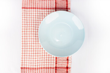 a blue  ceramic plates, set on a red and white tablecloth. isolated on white background