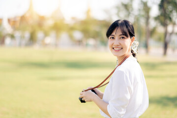 Portrait of asian woman traveler using camera. Asia summer tourism vacation concept with the grand palace in a background at Bangkok, Thailand