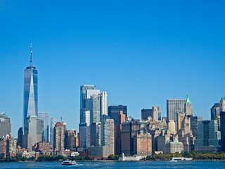 Obraz premium Looking back on Manhattan from the Hudson River and Liberty Island, as the towering high rises of Lower Manhattan loom above the river