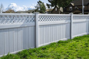 Nice new white wooden fence around house. Wooden fence with green lawn. Street photo