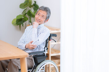 車椅子に乗った考えるシニア男性（介護・福祉）