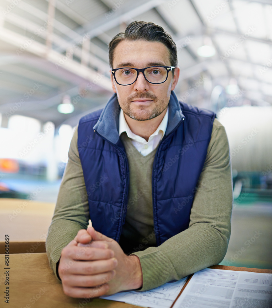 Poster Confidence in managing the factory floor. Portrait of a manager reading paperwork while standing on the factory floor.