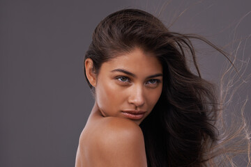 Feeling a little wild. an attractive young woman with windswept hair in studio.