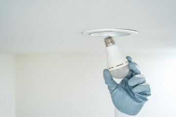Electrician installing led light bulbs at home for power saving. Fixing changing the Light Inside apartment. Home service concept.