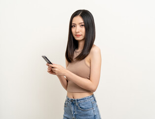 Naklejka premium Pretty young asian woman using smartphone standing on isolated white background. Excited Beautiful young asian shopping online payment with mobile phone. Playing game on smartphone