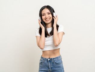 Cheerful asian female teenager listen to the music with white headphone dancing on isolated white background. Beautiful young woman in hand touch a wireless headphone having fun with music.