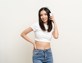 Cheerful asian female teenager listen to the music with white headphone dancing on isolated white background. Beautiful young woman in hand touch a wireless headphone having fun with music.
