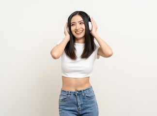 Cheerful asian female teenager listen to the music with white headphone dancing on isolated white background. Beautiful young woman in hand touch a wireless headphone having fun with music.