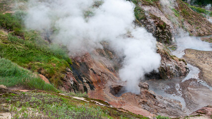 Fototapeta na wymiar Smoke is coming out of fumaroles in the Valley of Geysers in Kamchatka, Russia