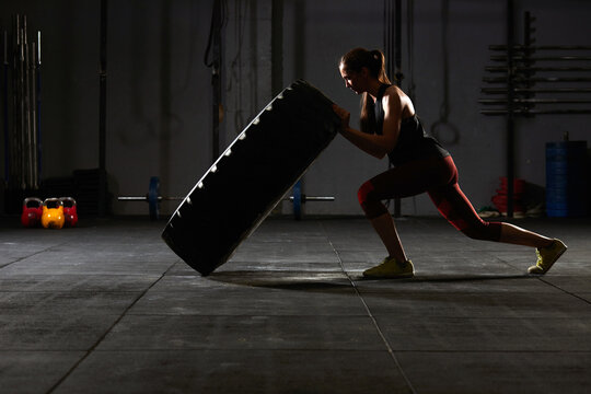 Woman flipping over a tractor tire.