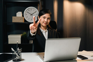 Lovely asian business woman working with laptop at night. Attractive female in suit work late at night overtime sitting in the dark room office.