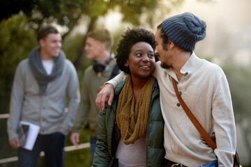 Fototapeta premium Whens your next class. an affectionate young couple on campus with other students in the background.