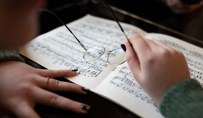 Hands of a girl with glasses on piano sheet music