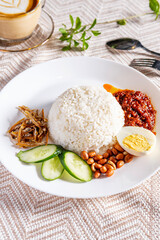 Nasi lemak is a Malay fragrant rice dish cooked with coconut milk. It is commonly found in Malaysia. It served with anchovies, egg, peanuts and chili paste. - 581676873