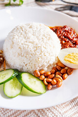 Nasi lemak is a Malay fragrant rice dish cooked with coconut milk. It is commonly found in Malaysia. It served with anchovies, egg, peanuts and chili paste. - 581676875