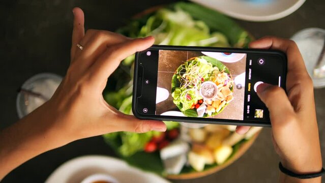 Young Woman Photographing Healty Organic Tofu Salad Using Smartphone from Above in Vegan Cafe, 4K Slow Motion Mobile Technology Concept, Thailand.