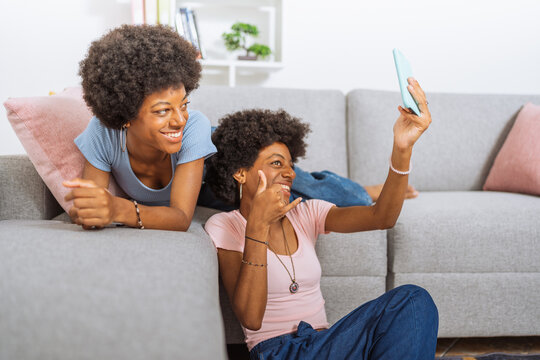 Twin sisters with afro hairstyle, making video calls with their cell phone to their friends