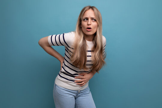 unhappy girl clutching her stomach due to illness on a blue isolated background