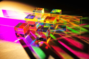 Artistic dispersion of artificial light, dichroic square glass cube and horizontal stripe scattering narrow beam of light into several colours of spectrum on texture white paper background.