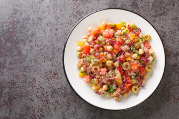 Healthy food appetizer salad of chickpeas, peppers, olives, tomatoes, green onions and amaranth microgreens and seeds close-up in a plate on the table. Horizontal top view from above