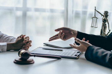 Fototapeta premium Lawyer working with client discussing contract documents with brass scales on law in courtroom Consulting to help clients win court cases.