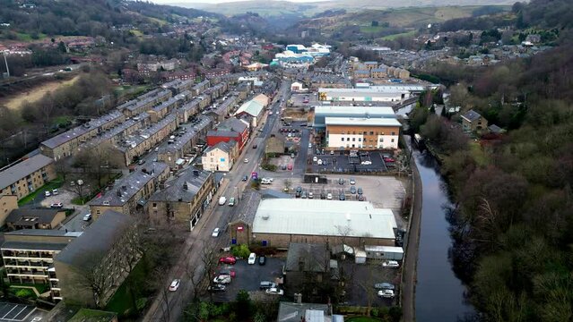 Drone shot of Halifax rd in todmorden north west yorkshire , this slow moving drone shot shows the quiet road with shops and greenery , with a lovely canal down the right hand side. 