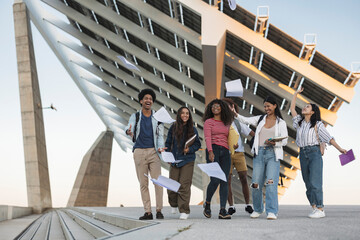 A group of diverse college students are excited to graduate from college. They are throwing papers...
