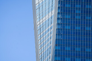 Fototapeta na wymiar Blue sky reflection in the windows of a modern glass skyscraper office building. Corporation headquarters buildings industry.