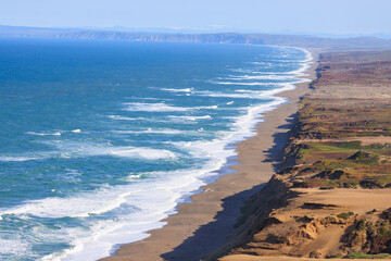 Steep sand dunes by long beach on coast of Marin County, California 