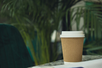 Eco recycling paper cup with coffee or tea on craft paper on table. Take away coffee to go. Copy space for text. Disposable Cardboard coffee outdoors