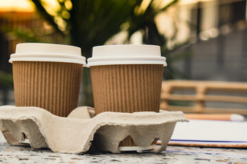 Two paper cups with lid for tea to go. Coffee take away on the table. Take-out coffees with brown...