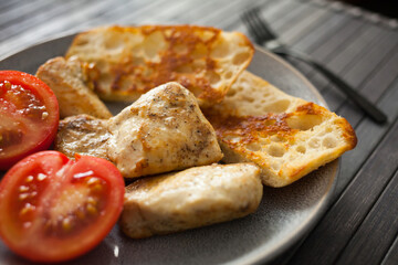 toasted pieces of chicken breast, toast and tomatoes on plate