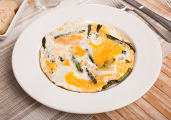 Closeup of fried eggs with asparagus at plate